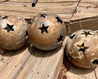 The three concrete spheres have star-shaped cutouts and a weathered bronze finish. 