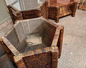 Woven wicker coffee and end table set includes one round glass-top coffee table and two hexagonal end tables. The set has a dark brown rattan-style texture and thick glass tops. Each piece is constructed with a sturdy pedestal base design.