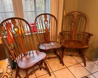 Set of 7 Windsor Style Wooden Oak Dining Chairs. Wooden dining chairs in a classic Windsor style with a medium brown finish. This set of seven has hoop-back designs with vertical spindles and a decorative central splat. The chairs have contoured seats and turned legs connected by H-stretchers. One of the seven is a captain's chair with arms.