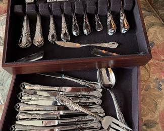 a wooden storage chest containing an ornate, traditional-style silver flatware set
