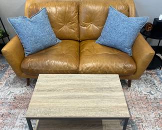 One of four matching modern cognac leather loveseats; one of nine matching modern industrial-style coffee tables.