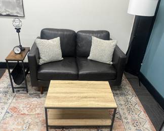 One of five matching modern black leather loveseats; one of nine matching modern industrial-style coffee tables; one of nine matching narrow end tables with black fabric magazine sling; excellent selection of lighting throughout.