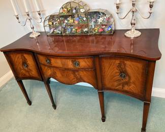 Hepplewhite-style serpentine sideboard featuring rich flame mahogany veneers and tapered spade feet. $3,000