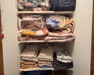 Some comforters and bedding shown and suitcase. There are more suitcases and comforters also