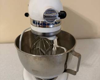 This white KitchenAid stand mixer comes with a stainless steel mixing bowl and a wire whip attachment, with the classic tilt-head or bowl-lift housing and speed control lever on the side. The bowl shows a handle and the body carries the original KitchenAid badging. Working condition not confirmed — worth a plug-in test before listing, but a well-known name that draws steady interest.