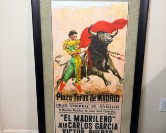 This framed bullfight poster advertises a corrida de novillos at the Plaza Toros de Madrid dated 1 de Mayo de 1993, listing matadors "El Madrileño," Juan Carlos García, and Víctor Puerto. The printed illustration shows a matador working a red cape against a charging bull, signed López Canito in the plate. It's presented under glass with a linen-look mat in a dark wood frame — a striking large-format piece of Spanish poster art.