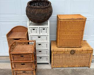This lot includes six wicker and rattan storage pieces: a large lidded wicker trunk with a brass-tone latch, a tall lidded hamper, a white-painted five-drawer wicker tower, a rattan-frame three-drawer stand, a small arched-back wicker shelf unit with a drawer, and a large woven basket in a darker natural finish. Sizes range from tabletop to floor-standing. A versatile lot for a sunroom, bedroom, nursery, or porch.
