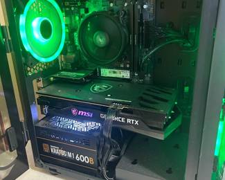 This CLX gaming desktop features a tempered glass side panel with RGB lighting, an AMD processor with air cooler, an M.2 SSD, an MSI GeForce RTX graphics card, and a Gamdias Kratos M1 600B power supply, all on an MSI motherboard. A top-mounted multi-port USB hub is attached. The system is shown powered on with lighting active.