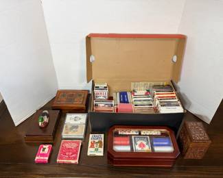 This lot includes a box packed with sealed and opened decks — Hoyle, Bicycle, and U.S. Playing Card Co. among them — plus a cased Texas Hold'em chip set with dice and a Bicycle deck. Also included are two wooden card boxes (one with an inlaid suit-motif lid), a carved wooden box, a duck-decorated wooden box, a novelty "Crooked Deck," a Crazy Eights card game, and a boxed art-back deck pair. A ready-made lot for a game room or card collector.