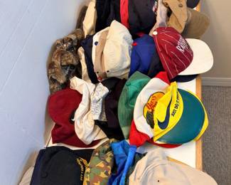 This large lot of ball caps includes a Bass Pro Shops/Nike cap, an Arkansas Razorbacks cap, a Pittsburgh cap, camouflage hunting caps, a Guinness cap, mesh trucker styles, and a range of solid and embroidered caps in assorted colors. Sizes and closures vary across the group, with both snapback and fitted styles present. A high-volume hat lot for resellers, collectors, or anyone who goes through caps.