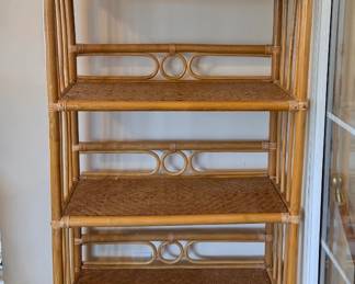 This rattan étagère features multiple woven cane shelves supported by a bamboo-style frame with decorative interlocking ring detail between each level. The natural finish and open construction keep it light-looking in a room. Good display or storage for a sunroom, bathroom, or bedroom.