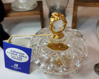 This cut crystal covered dish carries a Killarney Crystal Glass Co. Ireland hangtag and a gold seal marked "Guaranteed 24 Carat Gold," with a gold-finish figural lid handle. The body shows a deep-cut diamond and fan pattern that catches light well. Presented with the original tag attached — a nice small gift or collector piece.