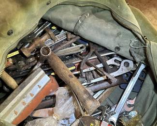 Assorted hand tools, wrenches, sockets, and hammers in a tool bag.