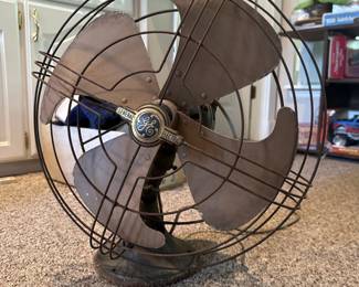 Vintage General Electric metal-blade floor fan with wire cage.