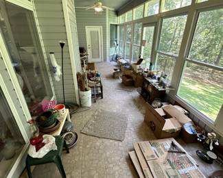 Sunroom or porch with plants, pottery, and household goods.