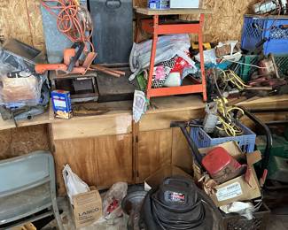 Shop bench with tools, power cords, boxes, and equipment.