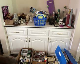 Sideboard cabinet with assorted collectibles, bottles, and decor.