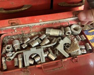 Socket sets, wrenches, and metal fittings in a red tool chest.