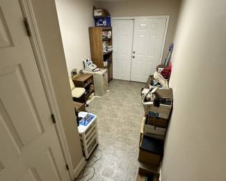 Storage hallway with boxes, shelving, and assorted household goods.