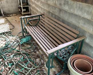 Metal garden bench, flower pots, garden hose, and outdoor furniture.
