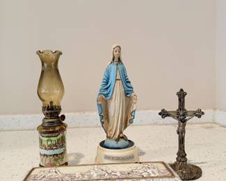 Religious decor with Virgin Mary statue, crucifix, and oil lamp.
