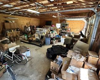 Packed workshop with tools, equipment, bicycles, boxes, and garage storage.