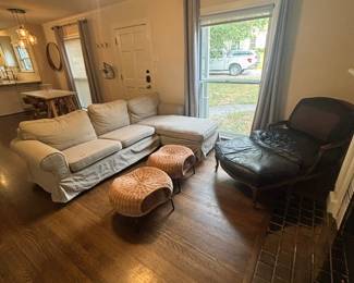 Slipcovered sofa, wicker ottomans, Two black leather French Provincial-style Bergère chairs with matching ottoman