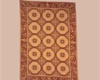 Warm gold and rust rug featuring repeating circular medallions and an ornate geometric border.