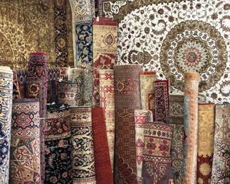 Large selection of rolled rugs featuring intricate traditional designs.