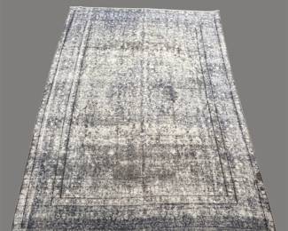 Soft gray and ivory distressed-style rug featuring a subtle traditional pattern and gently faded coloration.