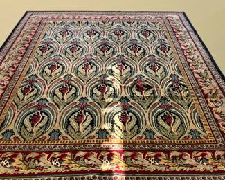 Blue and ivory rug featuring a flowing repeating decorative pattern with colorful floral-inspired detailing.