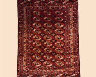 Deep red rug featuring a dense repeating traditional pattern in warm burgundy and brown tones.
