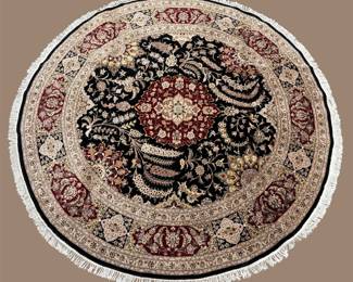 Round ivory, black, burgundy, and gold rug featuring an elaborate floral medallion with ornate scrolling details.