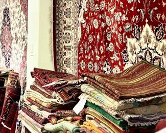 Colorful assortment of handmade rugs in rich reds, creams, and earth tones.