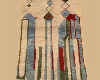 Unique ivory decorative rug featuring tall abstract architectural motifs in red, blue, black, gold, and green.