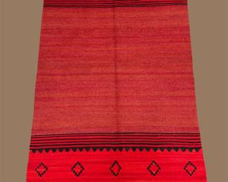 Rich solid red rug featuring subtle tonal texture and a decorative patterned border along one end.
