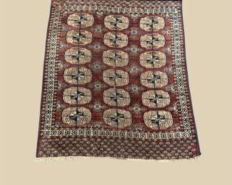 Dark rug featuring rows of repeating ivory and gold medallions surrounded by an intricate traditional border.