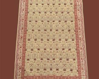 Neutral ivory rug featuring a small repeating all-over pattern and a warm rust-colored border.