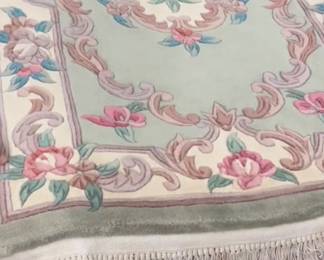 Close up of a soft floral rug with pastel pink, blue, and ivory details.