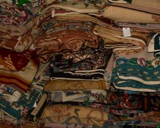 Stacked assortment of colorful folded rugs showcasing a variety of woven patterns, textures, and traditional designs.