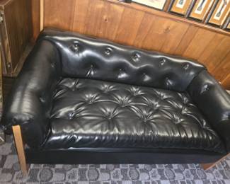 vintage black tufted leather (or faux-leather) mid-century modern loveseat or sofa with button-tufting and wood slab sides, similar in style to mid-century designs by makers like Adrian Pearsall, Percival Lafer, or Patrician Furniture Co..