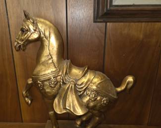 vintage gold-toned Chinese Tang Dynasty-style horse statue (often made of brass, bronze, or molded pottery like Freeman & McFarlin pieces) featuring a detailed saddle and draped harness.