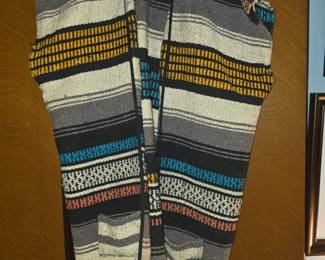 vintage Mexican serape blanket vest, often featuring a woven gray, black, beige, and turquoise striped pattern, front pockets, and fringed hem edges