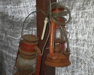 The selected region shows a pair of vintage red kerosene or utility lanterns (resembling Dietz Comet No. 50 or similar cold-blast models) hanging on a wooden post against a textured background