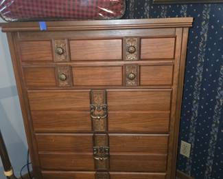 This piece appears to be a vintage mid-century modern wood tall chest of drawers (highboy), resembling designs from makers like the Dixie Furniture Co. (such as their Shangri-La line), featuring ornate brass-plated pulls and decorative vertical center molding
