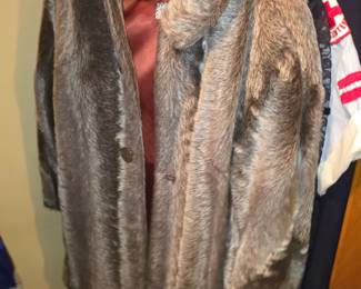 vintage brown faux fur or genuine fur jacket with a large lapel collar, a smooth maroon/burgundy lining, and front button closures hanging in a closet