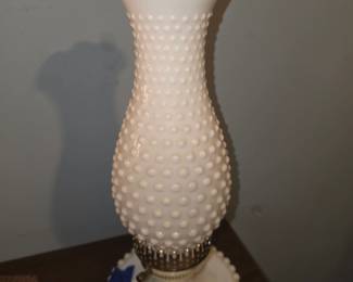 This is a vintage white milk glass hobnail hurricane or boudoir accent lamp with a ruffled crimped rim and a beaded or scalloped base.