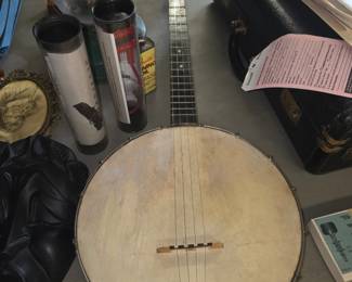 4-string tenor banjo with an open-back design, a skin or aged synthetic head, a wooden bridge, and a metal tailpiece.