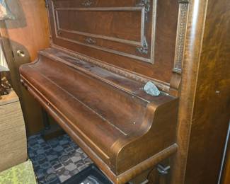 region shows an antique vintage upright piano (often referred to as an upright grand or cabinet grand piano) from the late 19th or early 20th century, featuring a rich dark wood/mahogany or walnut finish and ornate carved panels