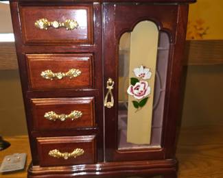 vintage wooden armoire-style jewelry box featuring four small drawers on the left and a side door with a floral painted or frosted glass panel
